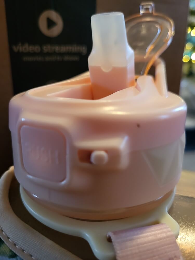 The opened drinking spout of the Cube Water Bottle. The button to open the lid as well as lock the lid are both visible.