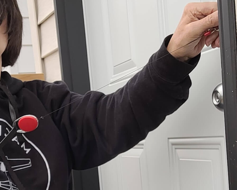 Close-up of the red retractable keychain and the black cord that is stretched toward the door.